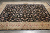 Load image into Gallery viewer, A rectangular area rug with an intricate floral pattern, featuring a black center field and a beige border, laid out on a gray tiled floor.