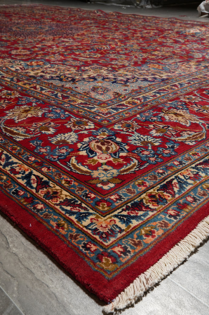 A traditional oriental area rug with a deep red field, detailed floral motifs, and cream fringe.