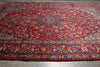 Load image into Gallery viewer, A large traditional oriental area rug with a vibrant red field, detailed floral motifs, and an ornate multi-colored border.