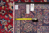 Load image into Gallery viewer, A close-up of an oriental area rug with a traditional floral pattern, shown next to a red patterned textile.  Two tags are pinned near the top edge to indicate its size. 