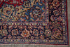 Load image into Gallery viewer, A close-up of a traditional oriental rug corner showing a dark navy blue field with intricate floral and vine motifs in red, beige, blue, and green, finished with a fringed edge.