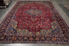 Load image into Gallery viewer, A traditional Persian-style area rug with a deep red central field, ornate floral motifs, and a dark navy blue border.