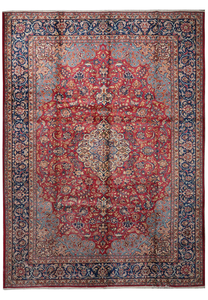 A traditional oriental area rug with a complex floral pattern, featuring a prominent red central medallion, a dusty blue-gray field, and a dark navy blue border.