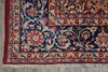 Load image into Gallery viewer, A close-up of an ornate Persian-style area rug corner, showing a deep navy blue field with intricate floral motifs in red, beige, and light blue, finished with white fringe.