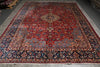 Load image into Gallery viewer, A traditional Persian-style area rug with a complex floral pattern, featuring a dominant red field, a central medallion, and a dark navy blue border with cream accents.