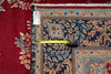 Load image into Gallery viewer, A close-up of an ornate patterned rug with a dark navy blue field, beige borders, and floral motifs in blue, green, and rust red. A yellow tape measure is placed horizontally across the rug to show its width, and a white product tag is visible on the left edge.