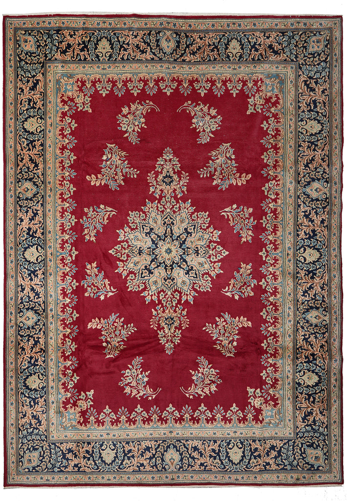 A traditional oriental area rug with a deep red central field, featuring a large central medallion and floral motifs in beige, navy blue, and muted green, surrounded by a detailed patterned border.