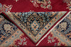 Load image into Gallery viewer, A folded traditional patterned rug shown in close-up, featuring a deep red field with floral motifs and a central dark navy section with ornate floral and vine borders in beige, blue, and red.