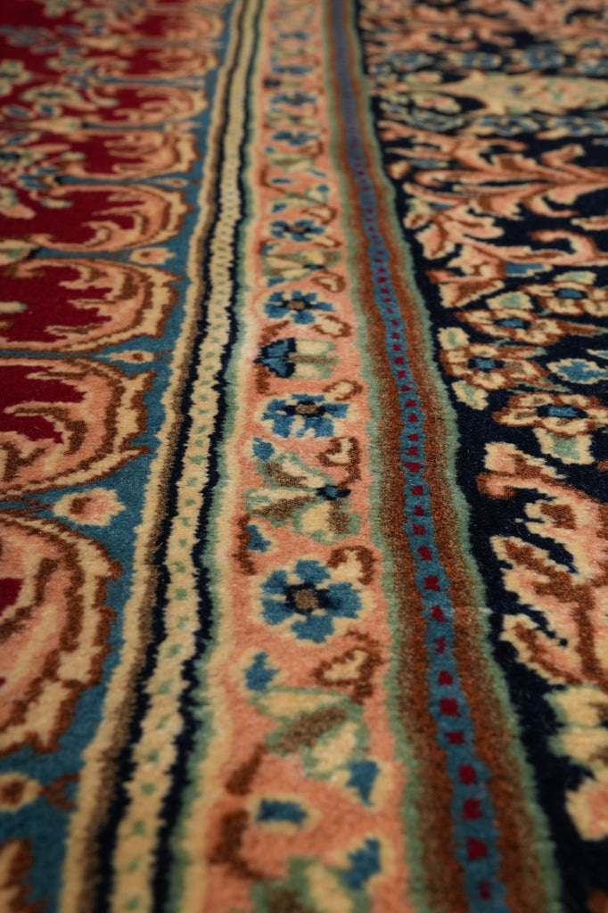 Close-up of a patterned area rug with ornate floral and geometric motifs in red, blue, beige, and brown tones.