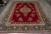 Load image into Gallery viewer, A traditional oriental area rug with a deep red field, featuring a central floral medallion and ornate borders in beige, navy blue, and green, laid out on a gray wooden floor.
