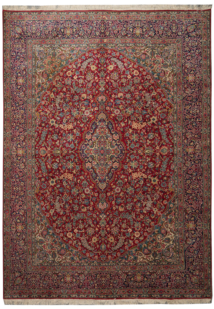 A traditional oriental area rug with an intricate floral pattern, featuring a large central medallion and a detailed border. The dominant color is a deep red, with prominent accents of blue, green, beige, and brown throughout the design.