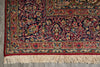 Load image into Gallery viewer, A close-up of an ornate traditional area rug with a complex floral and vine pattern in deep red, navy blue, beige, and green, featuring cream-colored fringe on the bottom edge.
