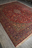 Load image into Gallery viewer, A traditional oriental area rug with a deep red field, intricate floral motifs, and a detailed border, shown laid out on a gray wood-look floor.