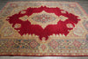 Load image into Gallery viewer, A traditional oriental area rug with a large red central medallion and ornate beige, gold, and blue floral borders, laid out on a gray wood floor.
