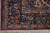 Load image into Gallery viewer, A close-up of a traditional Persian-style area rug showing its detailed floral pattern, deep navy blue field, and red and beige borders with white fringe.
