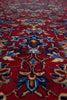 Load image into Gallery viewer, A close-up view of a traditional patterned rug with a deep red field, featuring intricate floral motifs in blue, beige, and brown.