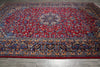 Load image into Gallery viewer, A traditional oriental area rug with a deep red field, intricate floral motifs, and detailed blue, beige, and gold borders, shown laid out on a gray tiled floor.