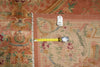 Load image into Gallery viewer, A close-up of a patterned area rug with a measuring tape laid across the corner and a small inventory tag attached, showing the rug's detail and scale.