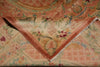 Load image into Gallery viewer, A close-up of a folded vintage patterned textile, likely a rug or tapestry, featuring a warm peach, pink, and beige floral design with fringed edges.