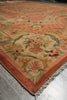 Load image into Gallery viewer, A close-up of an ornate area rug with a peach and rust border, cream field, and multicolored floral and scroll motifs, shown on a gray tiled floor.