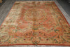 Load image into Gallery viewer, A traditional oriental area rug with a faded coral-pink center, beige borders, and multicolored floral and medallion motifs, laid out on a gray floor.