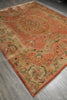 Load image into Gallery viewer, An ornate rectangular area rug with a warm terracotta and beige base, featuring intricate floral and medallion patterns in muted green, red, and blue, laid out on a gray wood floor.