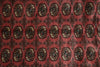 Load image into Gallery viewer, A close-up of a patterned textile or rug featuring a repeating medallion design in dark brown, black, and beige on a muted red background.