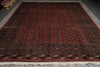 Load image into Gallery viewer, A large rectangular area rug with a deep red field, black and beige geometric borders, and repeating circular medallion motifs, photographed from above on a gray floor.