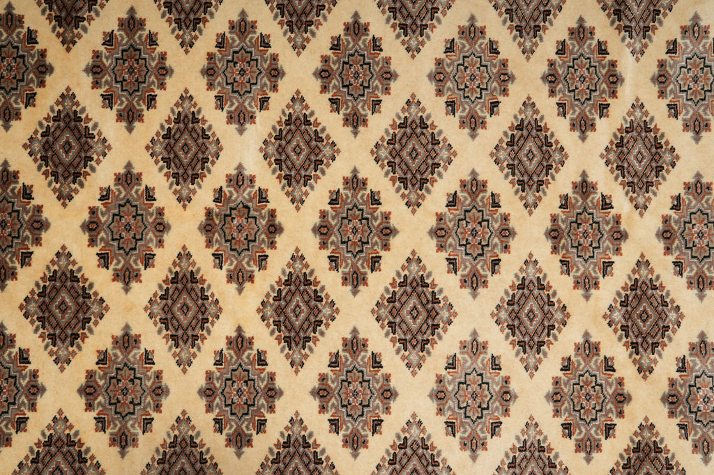 A close-up of a patterned textile or rug showing a repeating diamond motif in beige, brown, and muted blue tones.
