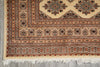 Load image into Gallery viewer, A close-up of a patterned area rug showing its corner, detailed geometric borders, and white fringe on a gray floor.