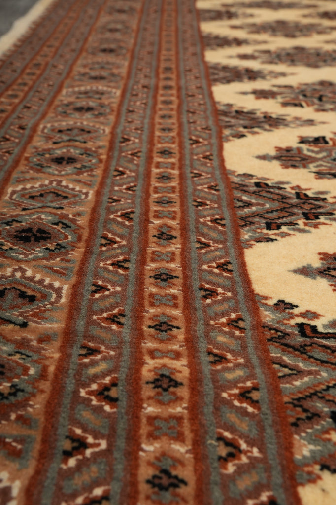 Close-up of a patterned rug showing woven geometric bands in brown, beige, muted blue-gray, and black.
