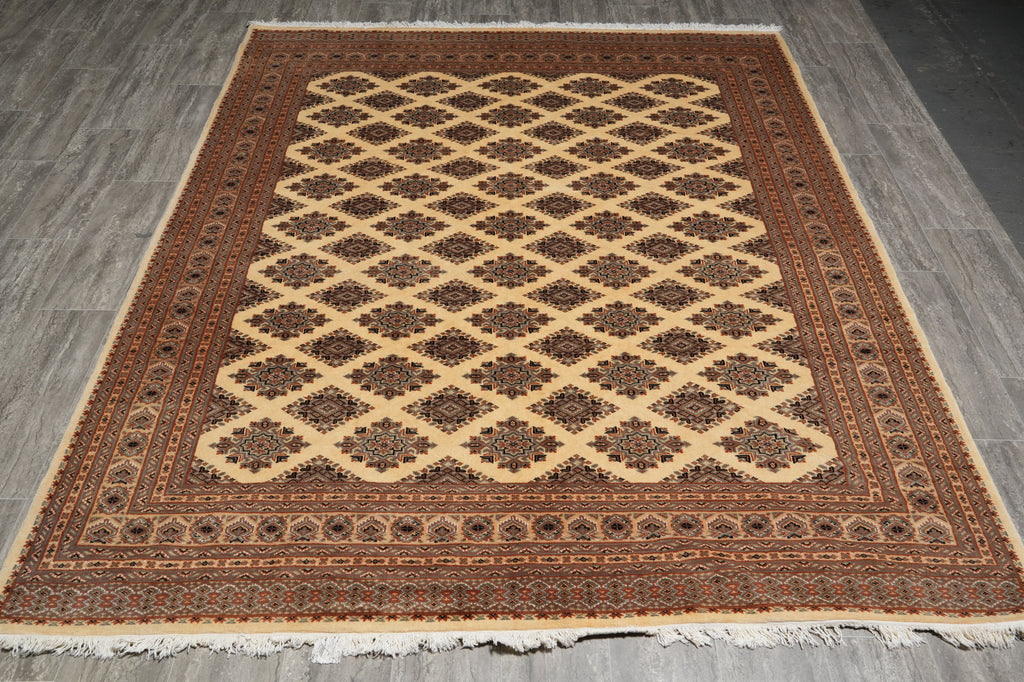 A rectangular area rug with a traditional Persian-style design, featuring a central diamond lattice pattern in beige over a dark brown field, surrounded by a detailed patterned border, laid out on a gray wood floor.