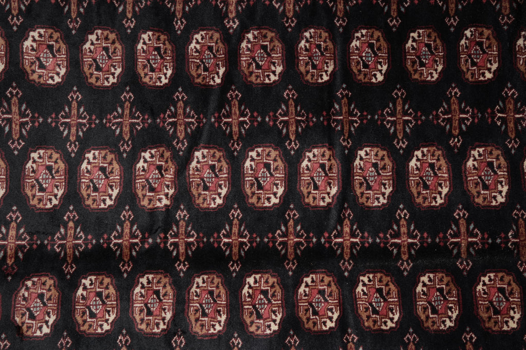 A close-up of a patterned textile featuring repeating ornate medallion motifs in rust red, beige, and black.