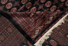 Load image into Gallery viewer, A close-up of a traditional patterned rug with a black base, intricate red, beige, and brown geometric motifs, and cream fringe on one corner.
