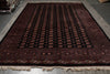 Load image into Gallery viewer, A large rectangular area rug with a dark red and black geometric pattern, displayed on a gray floor.