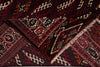Load image into Gallery viewer, A close-up of a folded patterned rug with geometric tribal designs in deep red, black, cream, and brown tones.