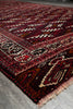 Load image into Gallery viewer, A close-up view of a traditional patterned rug with a deep red and black base, cream and beige geometric motifs, and fringed edges.