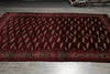 Load image into Gallery viewer, A long rectangular area rug with a deep red and black geometric pattern and a decorative border, laid out on a gray tiled floor.