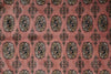 Load image into Gallery viewer, A close-up of a patterned textile or rug with a dusty pink background and repeating ornate medallion motifs in black, beige, and muted gold.