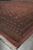 Load image into Gallery viewer, A close-up of a patterned area rug with a dusty rose field, dark brown borders, and cream fringe, laid on a gray floor.