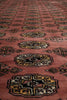 Load image into Gallery viewer, A close-up of a patterned rug with a dusty rose or terracotta pink field, featuring repeating geometric medallion motifs in black, yellow, and cream.
