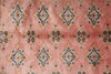 Load image into Gallery viewer, A close-up of a pink patterned fabric or rug featuring repeating geometric medallion motifs in navy blue, beige, and muted orange.