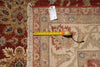 Load image into Gallery viewer, A close-up of an oriental-style area rug corner with fringe, showing a red and beige patterned design. A yellow tape measure is laid across the rug to indicate size, with a white product tag attached.