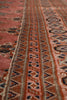 Load image into Gallery viewer, Close-up of a patterned rug with a dusty rose pink field, a central border of repeating geometric motifs in navy, rust, and beige, and a lower border with circular medallions.
