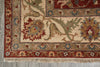 Load image into Gallery viewer, A close-up of a traditional patterned rug corner showing cream, red, green, and blue floral motifs with a fringed edge on a gray floor.