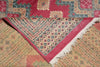 Load image into Gallery viewer, A folded patterned rug with a dusty pink border and cream fringe, layered over another rug featuring beige, red, and blue geometric motifs.