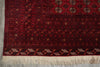 Load image into Gallery viewer, A close-up of a traditional patterned rug with a deep red field, geometric borders, and cream fringe at the bottom.