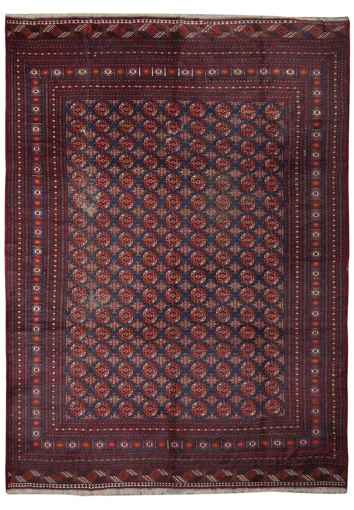 A traditional rectangular area rug with an intricate geometric pattern in deep red, navy blue, and beige, featuring a detailed border and central field.