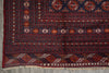 Load image into Gallery viewer, A traditional patterned rug with a dark navy blue field, red borders, and cream geometric motifs, laid flat on a gray concrete floor.