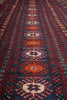 Load image into Gallery viewer, A close-up of a patterned rug with geometric and floral motifs in red, navy blue, orange, and cream, showing the detailed woven texture.